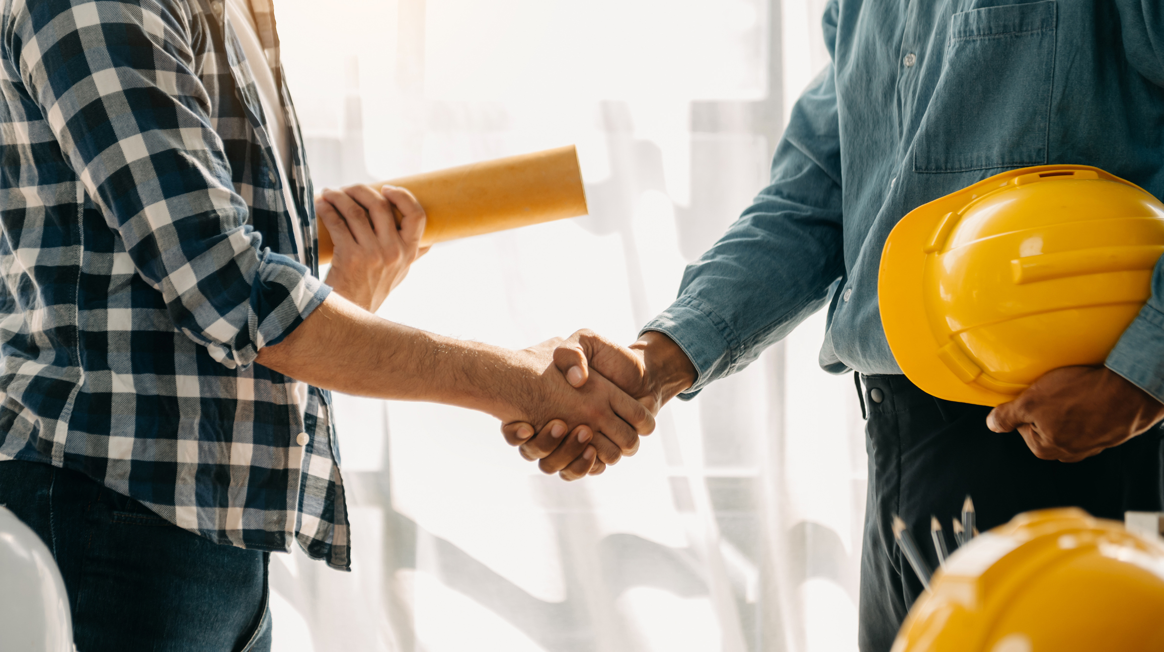Construction team shake hands greeting start new project plan behind yellow helmet on desk in office center to consults about their building project. Pittsville, WI: Cold Storage Warehouse Distribution Facility